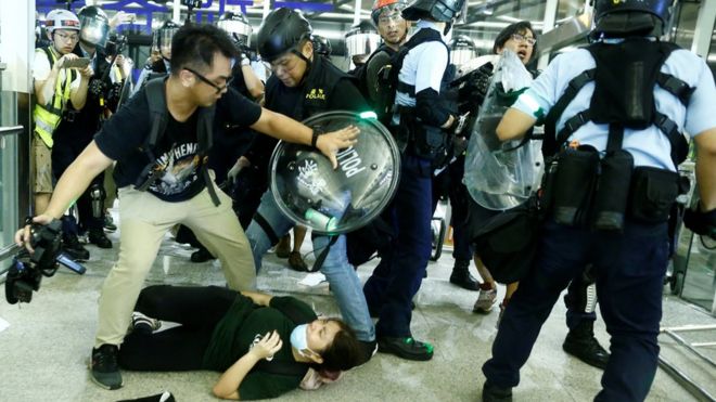 ОМОН использует перцовый баллончик для разгона протестующих против законопроекта об экстрадиции во время массовой демонстрации в международном аэропорту Гонконга после ранения женщины в глаз