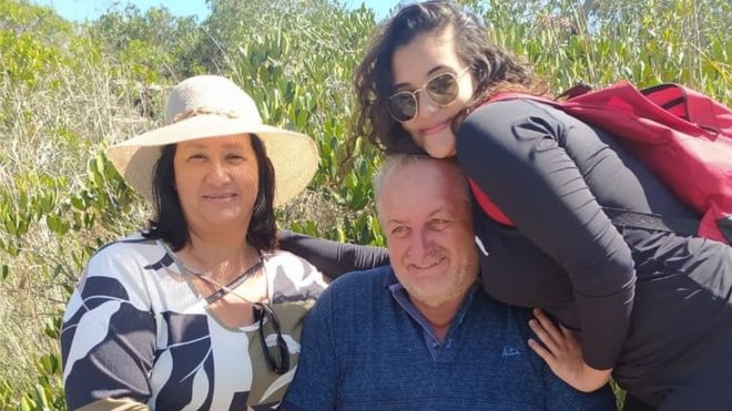 Giovana posa abraçada com os pais em foto ao ar livre