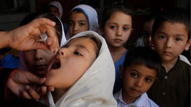 Пакистанский медработник дает вакцину от полиомиелита студенту в школе в Пешаваре, Пакистан, понедельник, 18 апреля 2016 года.