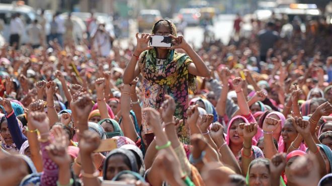 Женщина из индийского профсоюза работников фотографирует на мобильный телефон во время акции протеста в Ахмадабаде 12 февраля 2017 года.