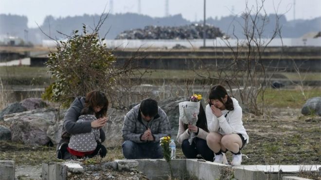 Toshiaki Fujita (2nd-L), 47, offers a prayer for his late mother Toshiko, who died in the Tsunami in Fukishima province (11 March 2016)