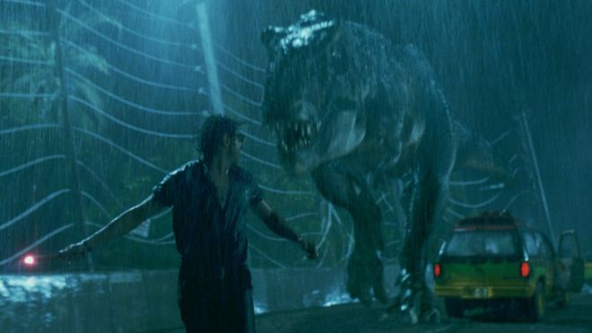 Сцена из фильма «Парк Юрского периода» - человек бежит от тиранозавра под дождем