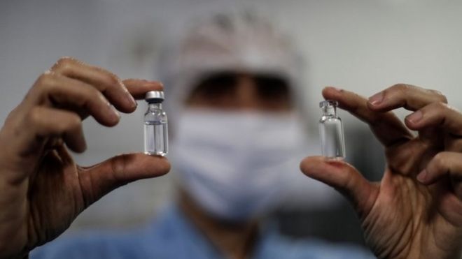 Homem segura frasco da vacina de Oxford
