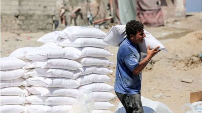 Un Palestinien porte un sac de farine fourni comme aide aux familles au centre de distribution de l'Office de secours et de travaux des Nations Unies pour les réfugiés de Palestine (UNRWA), dans le camp de réfugiés d'Al-Shati, dans la ville de Gaza, le 31 juillet 2023.