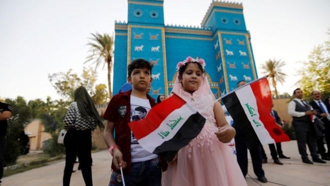 Дети держат иракские флаги во время празднования после того, как ЮНЕСКО объявило Вавилон объектом Всемирного наследия перед точной копией ворот Иштар возле Хиллы, Ирак, 5 июля 2019 года.