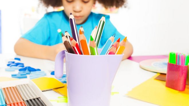 Criança desenhando com lápis coloridos em escola