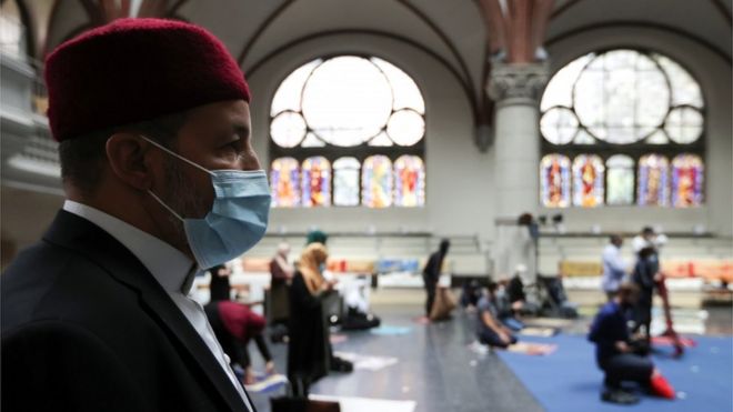 A Muslim man wearing a face masks prays at a church in Berlin