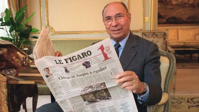 French industrialist and politician poses with a copy of French newspaper Le Figaro in Paris on 5 February 2002.