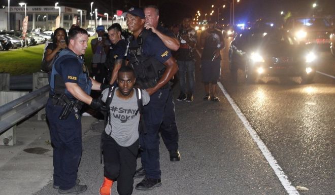 Активист полиции арестовывает Дерея МакКессона во время акции протеста вдоль шоссе авиакомпании, главной дороги, которая проходит перед штаб-квартирой полицейского управления Батон-Руж Суббота, 9 июля 2016 г.