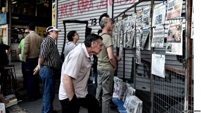 Люди читают газеты в центре Афин 30 июня 2015 года.