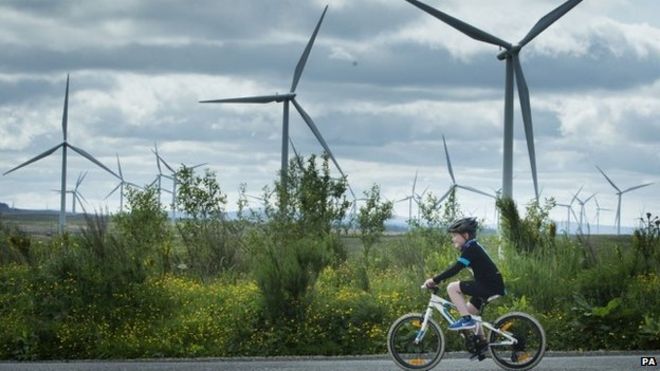 Мальчик катается на велосипеде на фоне ветряной электростанции