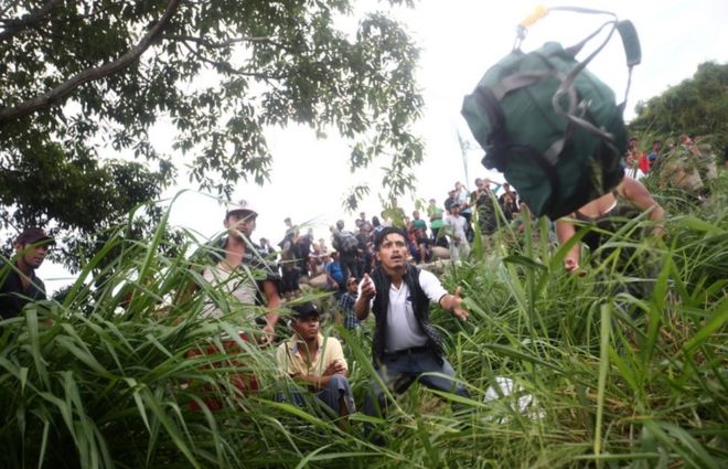 Гондурасец ловит брошенный ему рюкзак после пересечения реки Сушиат