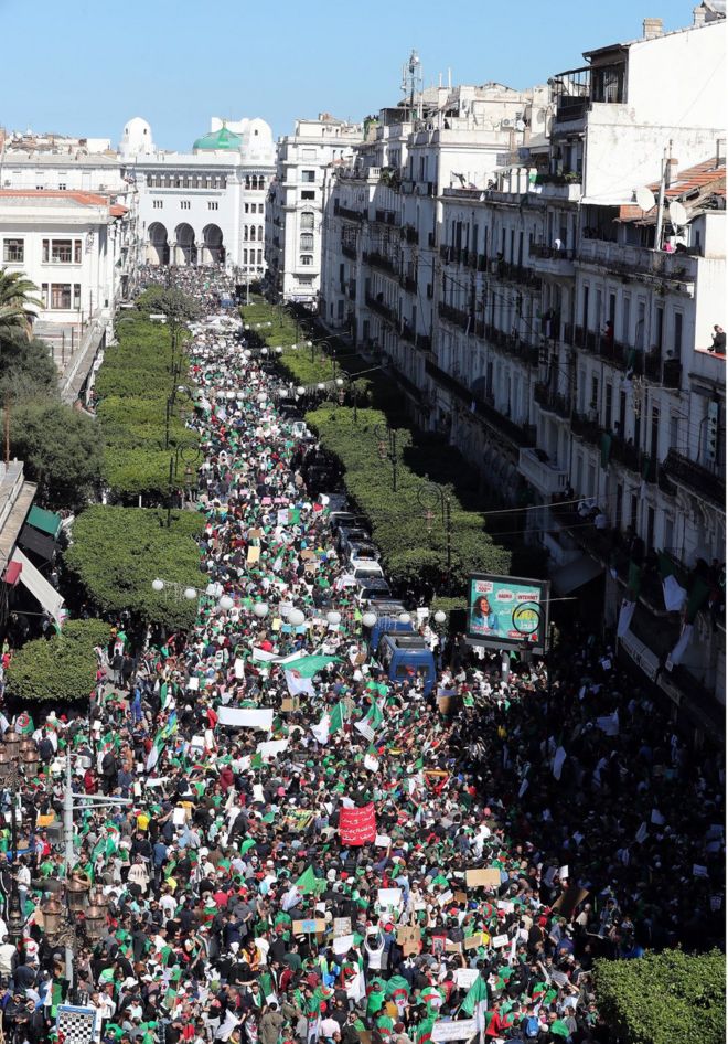 Алжирцы протестуют против президента Абдельазиза Бутефлики, изображенного в столице страны Алжире 15 марта 2019 года.