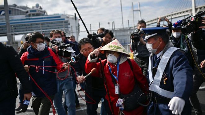 Пассажир (в центре R) уходит пешком после выхода из круизного лайнера Diamond Princess на карантине из-за опасений по поводу нового коронавируса COVID-19 на круизном терминале Daikoku Pier в Иокогаме 19 февраля 2020 года.