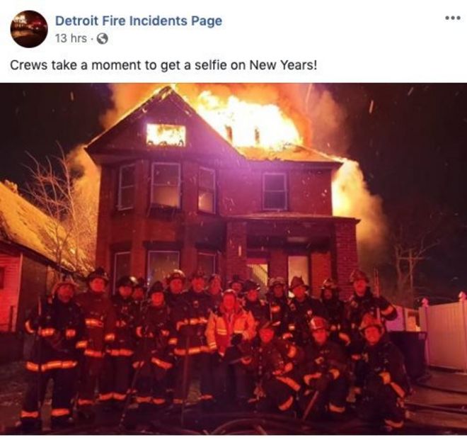 the photo of firefighters posing in front of a burning building