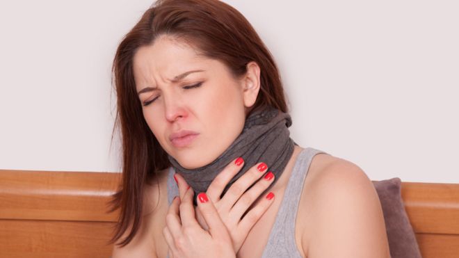 Mujer con las manos en el cuello y dolor de gargant