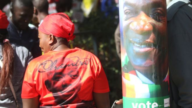 Сторонник MDC (слева) у плаката кандидата Зану-ПФ Эммерсона Мнангагвы в Хараре, Зимбабве