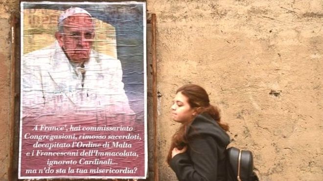 Una joven pasa por el lado de un cartel del Papa