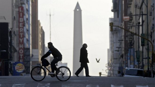 People cross an almost deserted avenue in Buenos Aires on July 10, 2009.