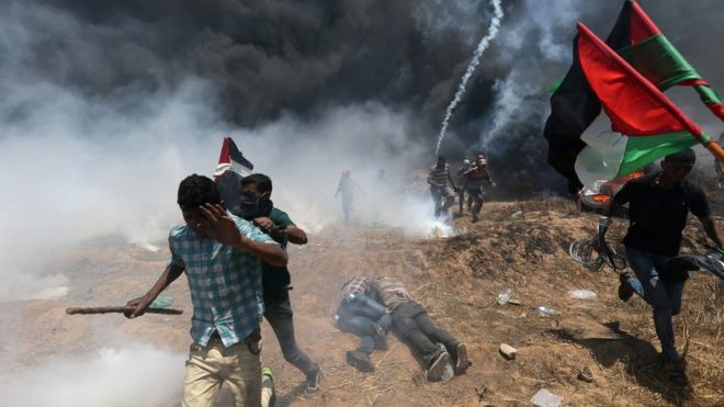 Палестинцы бегут в укрытие во время акции протеста у забора границы между Газой и Израилем (14 мая 2018 года)