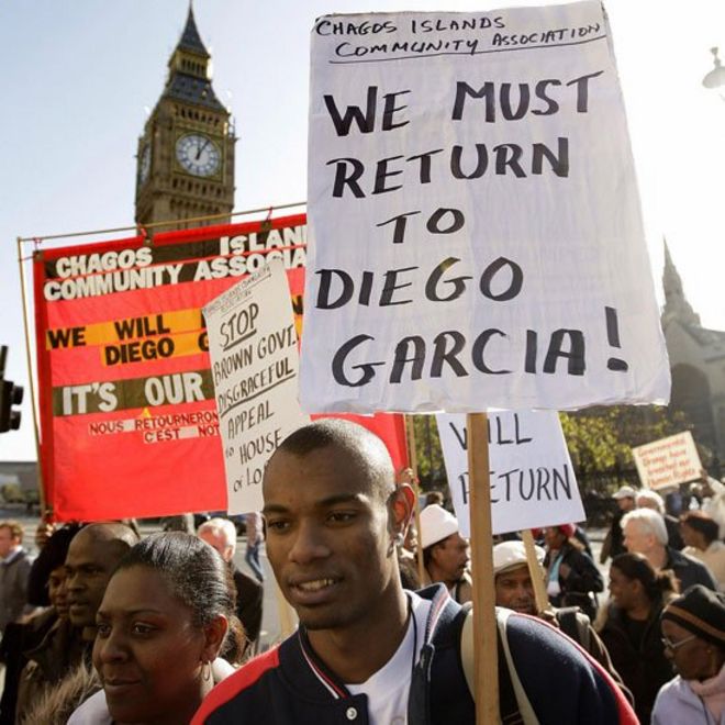 Joven con un carteL que dice "Debemos regresar a Diego Garcia"