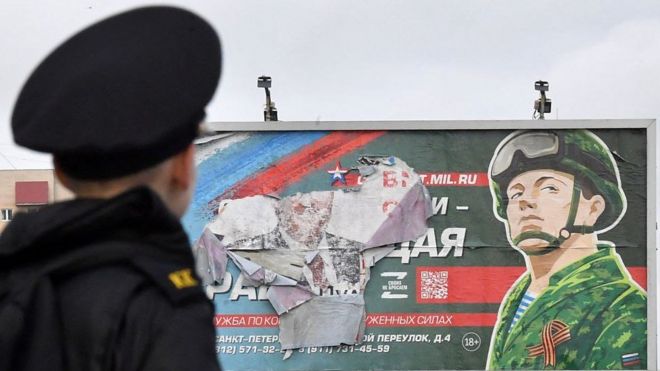 Курсант смотрит на плакат с солдатом