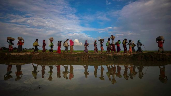 Беженцы рохингья отражаются в дождевой воде вдоль набережной рядом с рисовыми полями после бегства из Мьянмы в Паланг Хали, недалеко от базара Кокса, Бангладеш