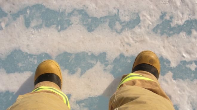 Две ноги в пожарном снаряжении, стоящие на морском льду