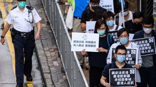Протестующие, выступающие за демократию, держат черные плакаты, приближаясь к китайскому офису связи в Гонконге