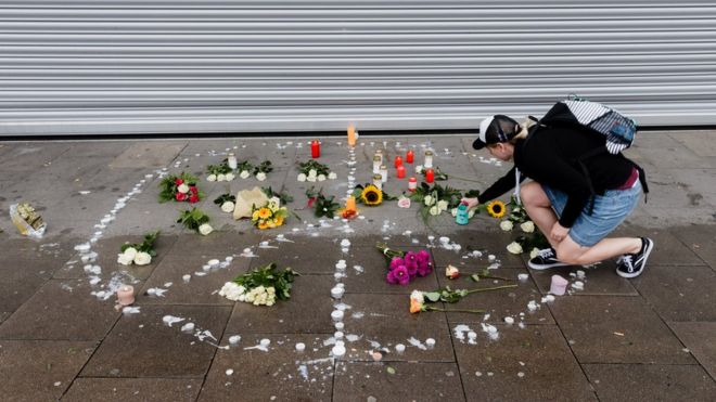 Женщина ставит свечу у импровизированного мемориала, установленного как знак мира, на месте нападения ножа в северном немецком городе Гамбург, 29 июля 2017 года