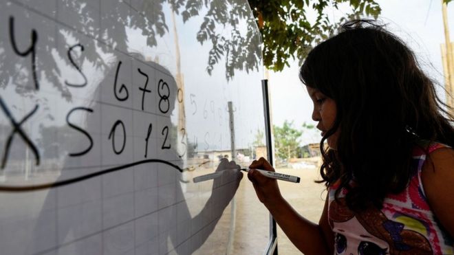 Una niña escribiendo números en una pizarra.