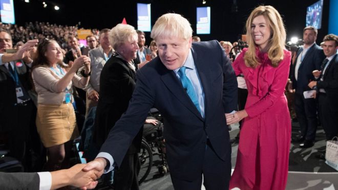 Премьер-министр Борис Джонсон покидает сцену со своей партнершей Кэрри Саймондс после выступления на конференции Консервативной партии в конференц-центре Манчестера.