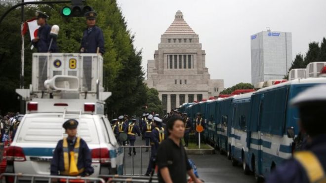 Улицы перед зданием парламента заблокированы полицейскими машинами во время акции протеста в Токио (18 сентября 2015 года)