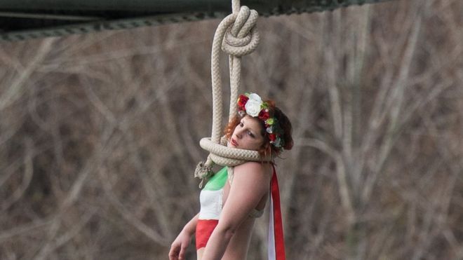 Активистка Femen, Сара Константин, повешена на петлеобразной веревке на парижском мосту, чтобы привлечь внимание к большому количеству казней в Иране, когда она устраивает акцию протеста против визита президента Ирана Хасана Рухани в Париж, в четверг, 28 января, 2016.