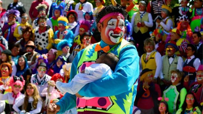 Клоун держит ребенка на съезде клоуна