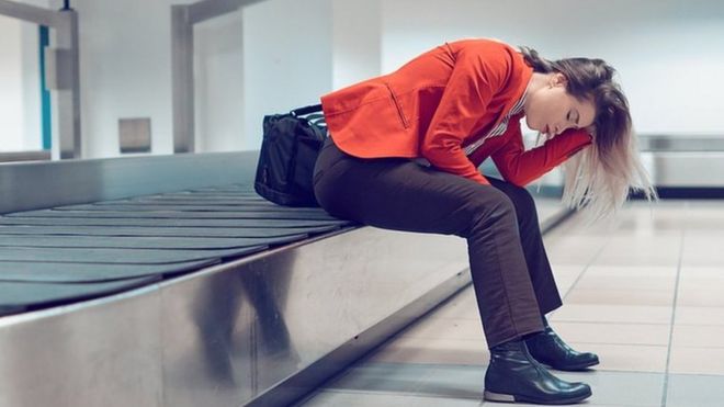 Женщина, опустив голову на руки, сидит на чемоданной карусели