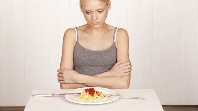 Mujer delgada frente a un plato de comida