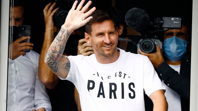 Lionel Messi waving to fans wearing a Paris t-shirt