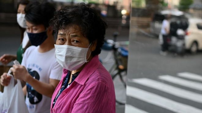 Пожилая женщина в маске идет по улице Токио 9 июня 2020 года.