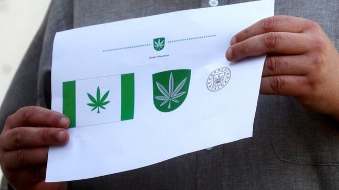 Дизайнер Тону Кукк держит бумагу с изображением флага муниципалитета Канепи