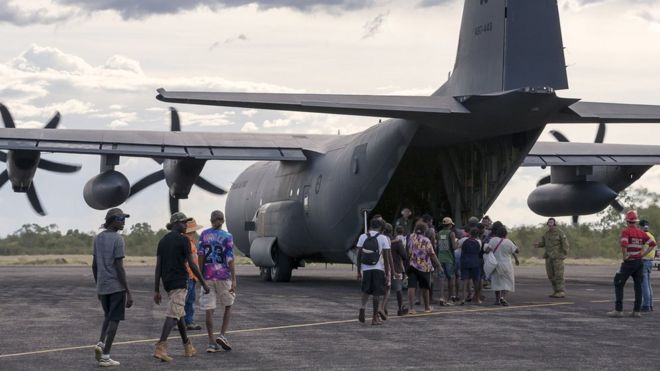 Жители Макартур-Ривер, отдаленного города в Северной Территории, садятся на военный самолет во время эвакуации перед Циклон Тревор.