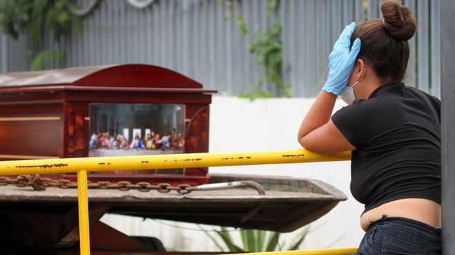 Woman standing by a coffin in Guayaquil, Ecuador