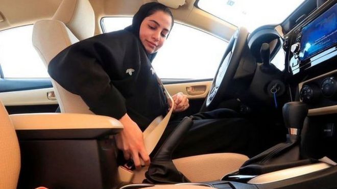 Saudi woman buckling her seatbelt before doing a driving test at the General Department of Traffic