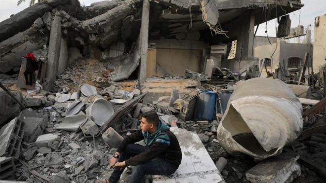 فلسطينيون يتفقدون منزلا مدمرا في دير البلح، وسط قطاع غزة