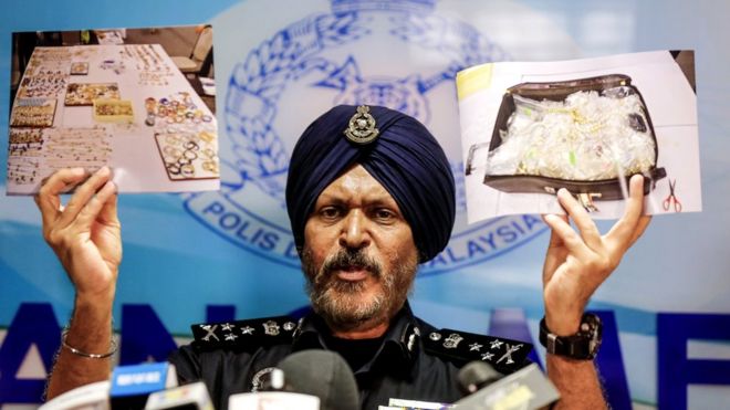 Полицейский демонстрирует фотографии предметов с рейда во время пресс-конференции в Куала-Лумпуре, Малайзия, 27 июня 2018 года.