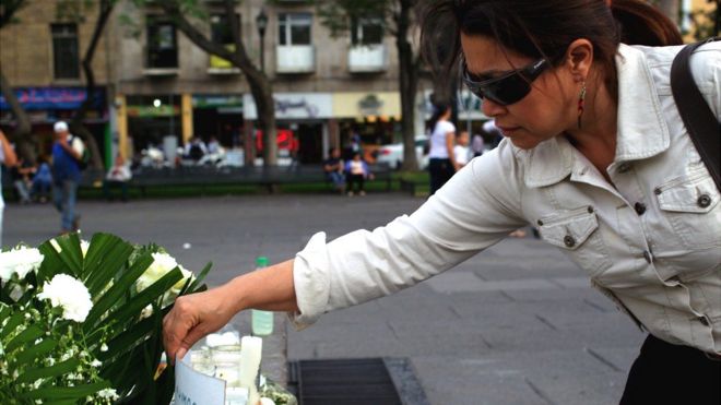 Mujer poniendo un ramo de flores para homenajear a los muertos.