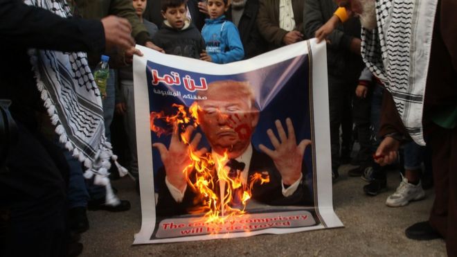 Palestinians protest against President Trump's Middle East peace plan by burning a poster of Mr Trump