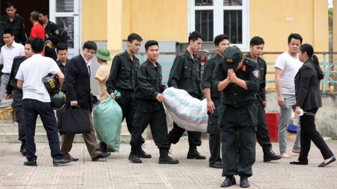 Полицейский кланяется, выходя из коммуны Донг Там на окраине Ханоя, Вьетнам, с 19 заложниками, которые первоначально содержались в земельном споре, 22 апреля 2017 года