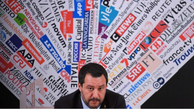 Salvini participa de coletiva de imprensa, com plano de fundo estampado com marcas de veículos de imprensa