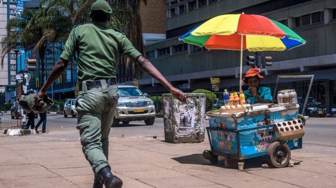 Зимбабвийский солдат проходит мимо уличного торговца по центральным деловым улицам Хараре 20 ноября 2017 года